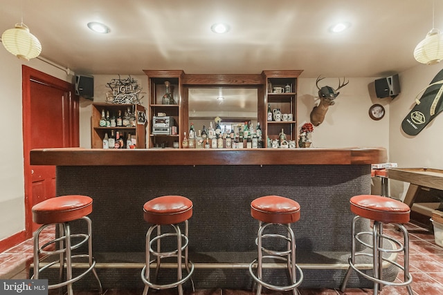 bar featuring decorative light fixtures and dark tile floors