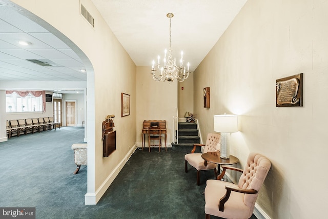 sitting room with a drop ceiling, dark colored carpet, and a chandelier