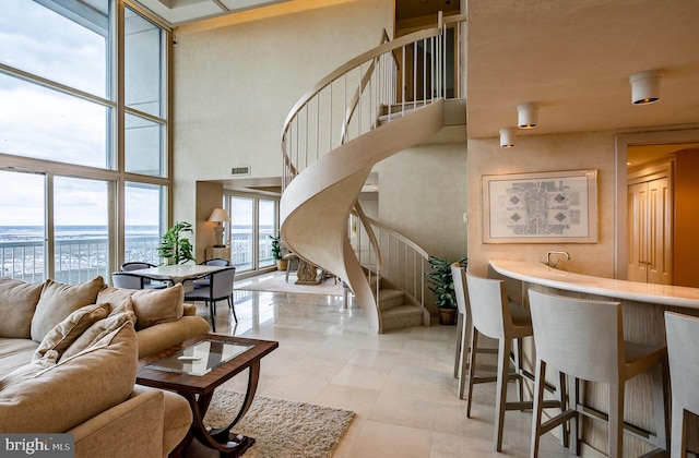 tiled living room with a wall of windows and a towering ceiling