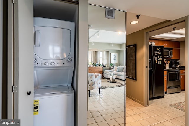 laundry area with stacked washer and clothes dryer and light tile floors