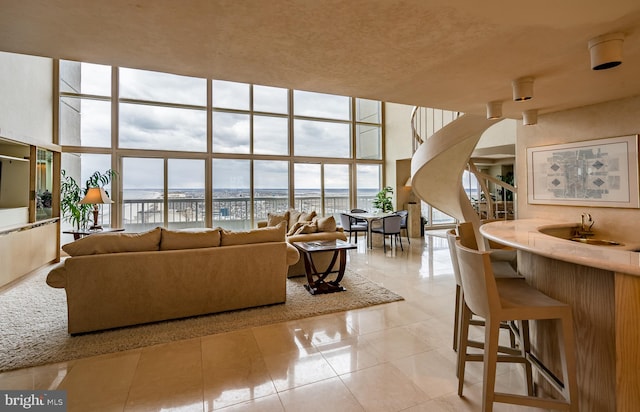 tiled living room featuring sink, a wall of windows, and a high ceiling