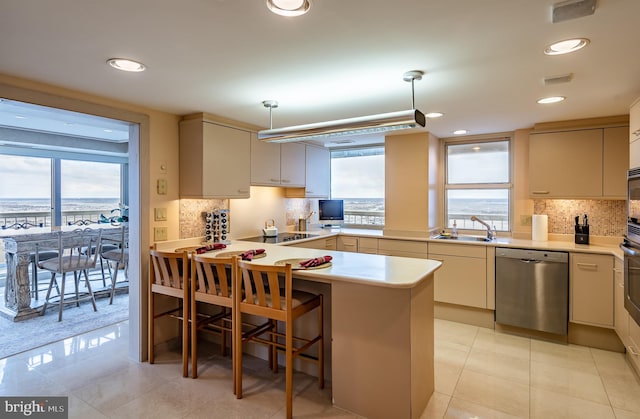 kitchen featuring appliances with stainless steel finishes, sink, light tile flooring, tasteful backsplash, and decorative light fixtures