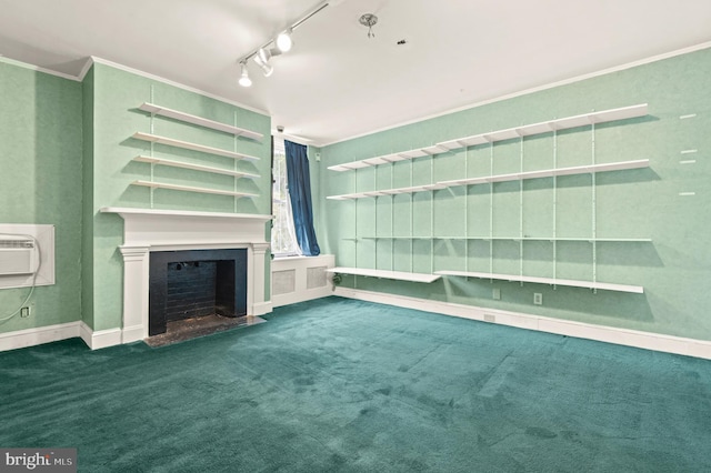 unfurnished living room with ornamental molding, a wall unit AC, dark carpet, and rail lighting