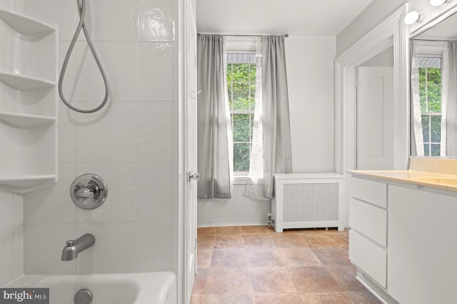 bathroom featuring tile floors, tiled shower / bath combo, radiator heating unit, and vanity