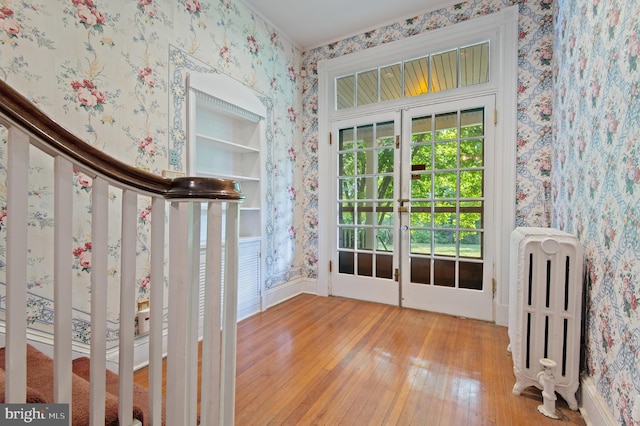 doorway to outside featuring built in features, french doors, light wood-type flooring, and radiator