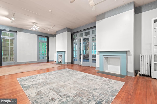 living room with hardwood / wood-style floors, ceiling fan, track lighting, and radiator heating unit