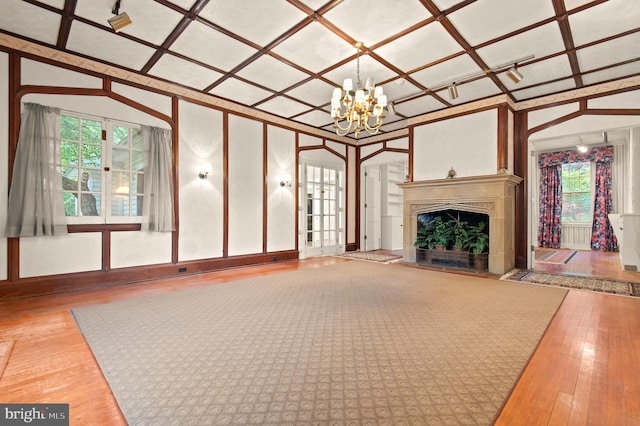 unfurnished living room featuring a notable chandelier, lofted ceiling, hardwood / wood-style flooring, and coffered ceiling