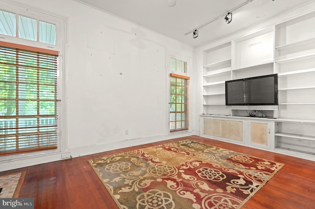 living room with built in features, plenty of natural light, dark hardwood / wood-style floors, and track lighting