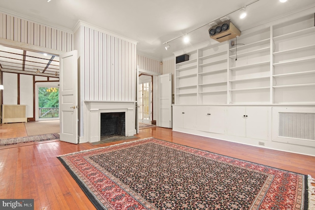 unfurnished living room with ornamental molding, track lighting, and light wood-type flooring