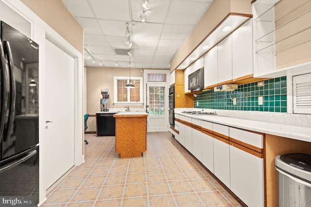 kitchen with decorative light fixtures, white cabinets, black appliances, rail lighting, and backsplash