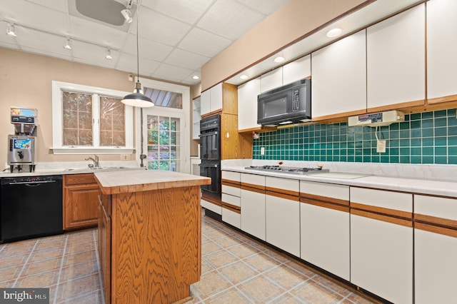 kitchen featuring decorative light fixtures, backsplash, a kitchen island, black appliances, and rail lighting