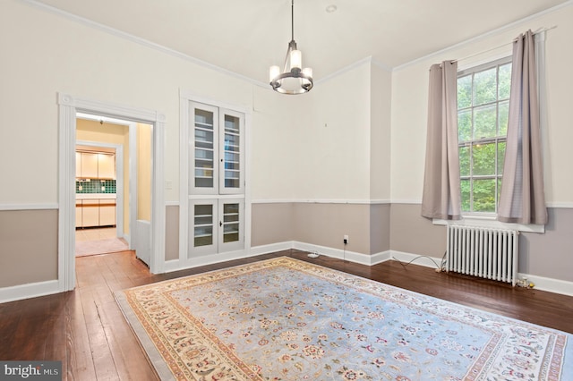 spare room with a wealth of natural light, radiator, hardwood / wood-style flooring, and a chandelier