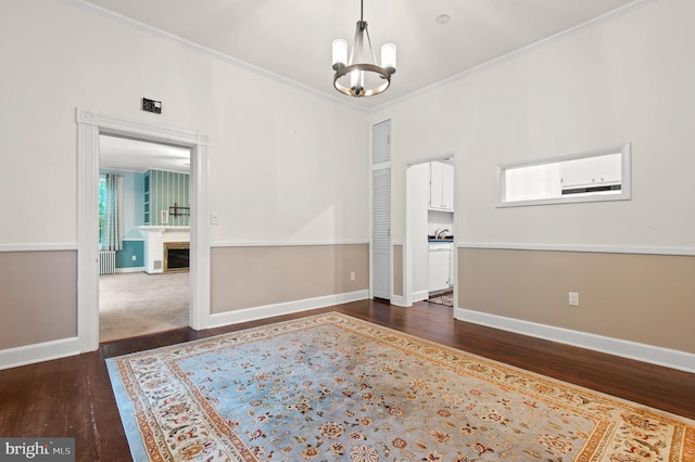 unfurnished room with dark wood-type flooring, crown molding, an inviting chandelier, and radiator heating unit