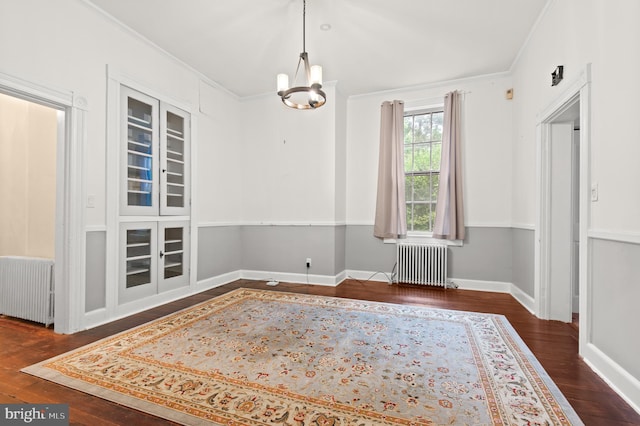 unfurnished room with an inviting chandelier, crown molding, radiator, and dark wood-type flooring