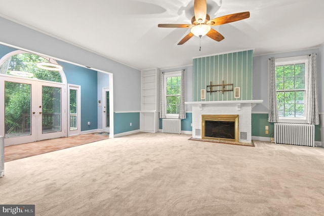 unfurnished living room featuring a fireplace, ceiling fan, plenty of natural light, and radiator heating unit