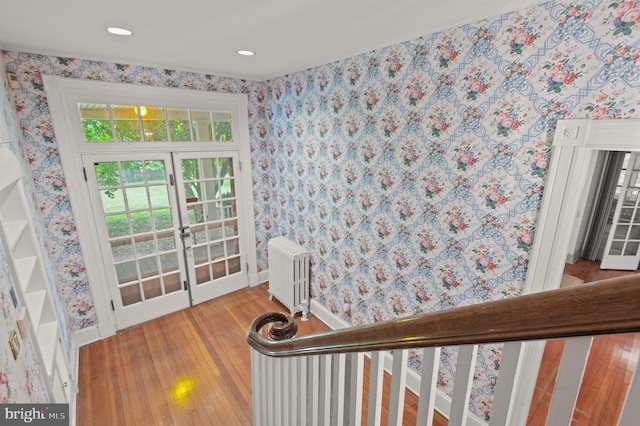 stairway with french doors, radiator heating unit, and light wood-type flooring