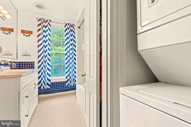 laundry area featuring stacked washing maching and dryer and light tile floors