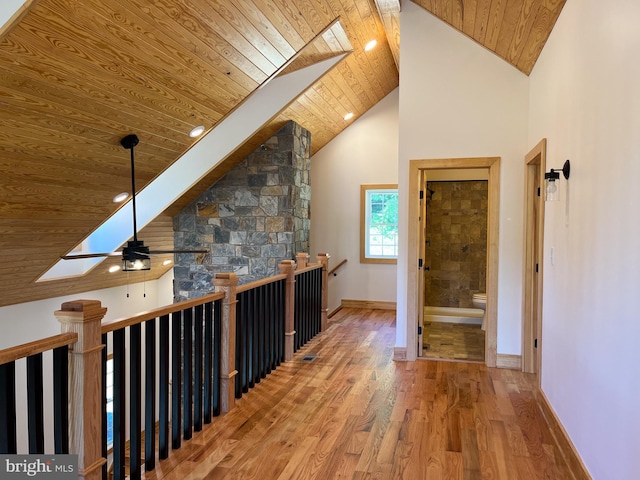 corridor with high vaulted ceiling, a skylight, wood ceiling, and hardwood / wood-style flooring