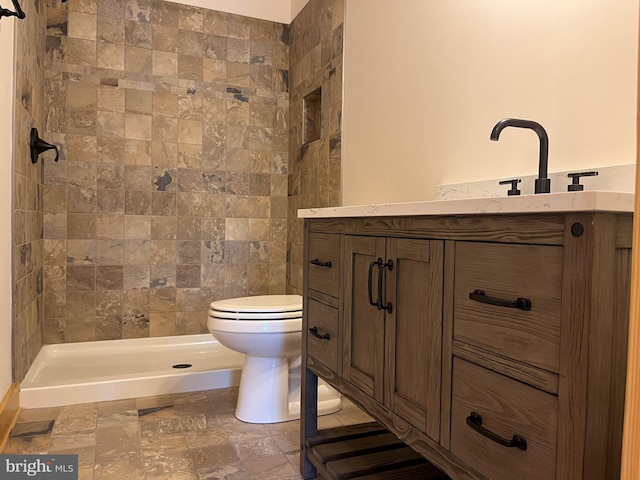 bathroom featuring toilet, vanity, and a tile shower