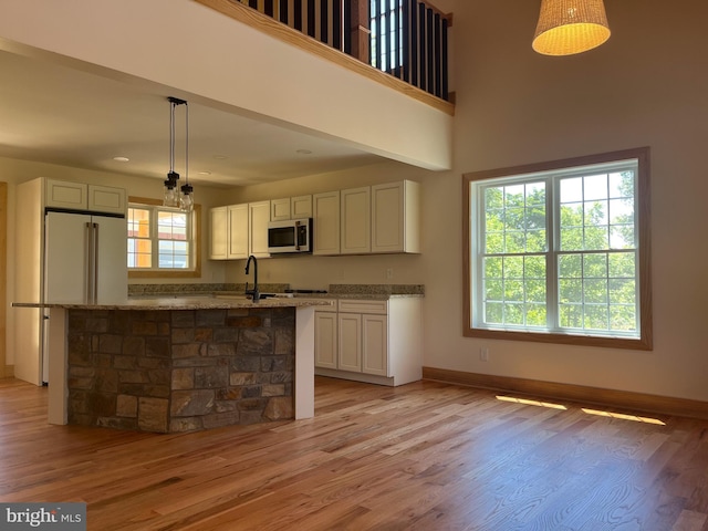 kitchen featuring white cabinets, light stone counters, light hardwood / wood-style flooring, and pendant lighting