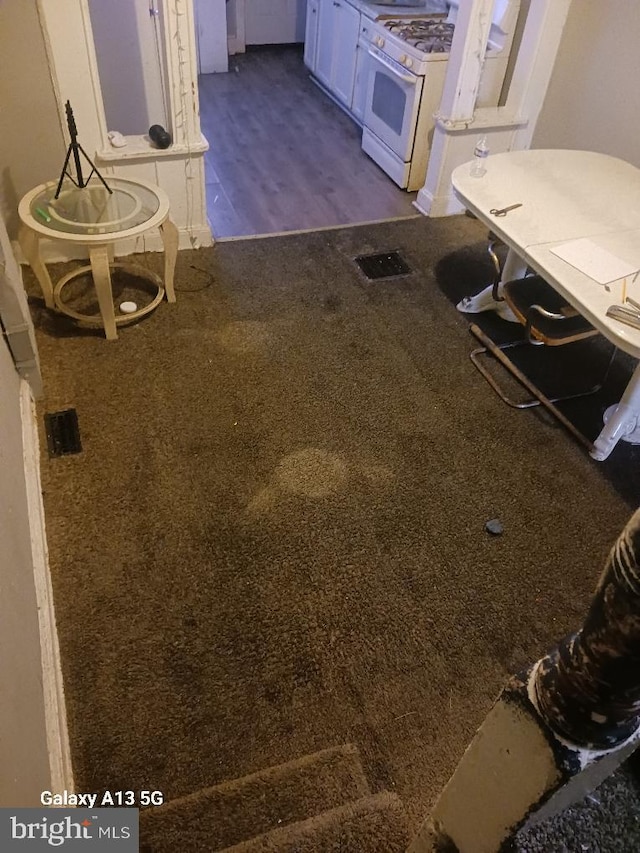 interior space with white gas range, carpet floors, and white cabinetry