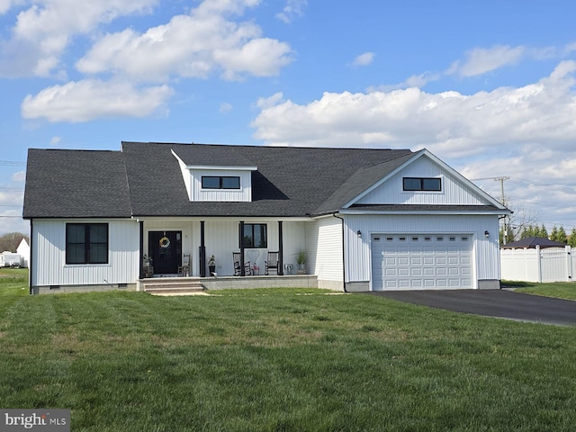 modern farmhouse featuring a garage, covered porch, and a front lawn