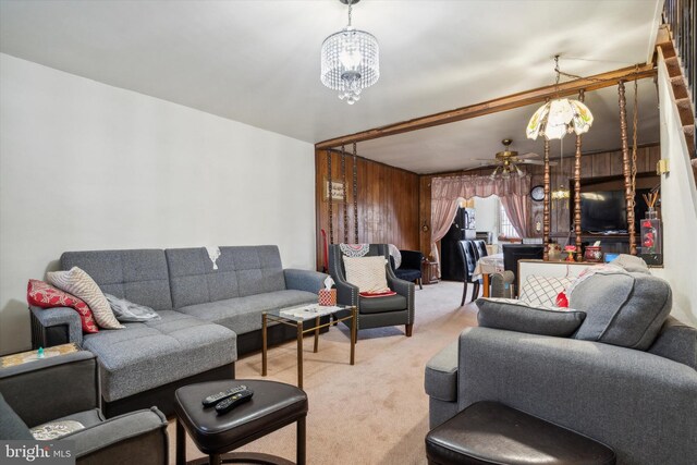 living room with wood walls, ceiling fan with notable chandelier, and light colored carpet