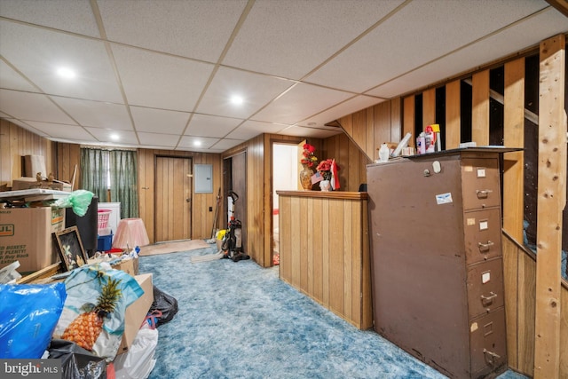 basement featuring carpet, electric panel, and wooden walls