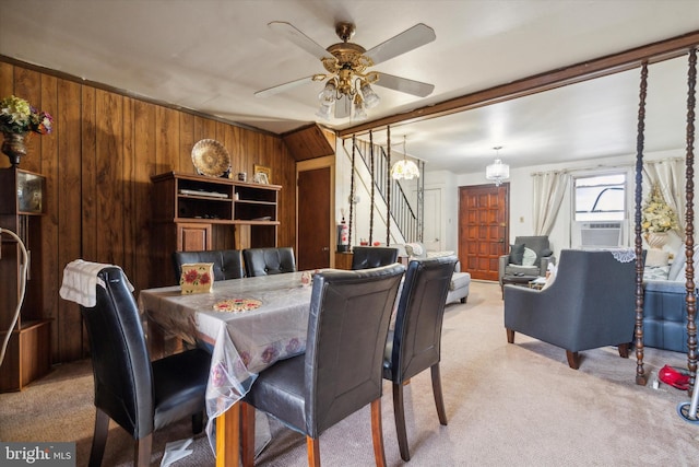 carpeted dining space with cooling unit, ceiling fan, and wood walls