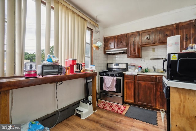 kitchen featuring tasteful backsplash, a healthy amount of sunlight, stainless steel gas range, and light hardwood / wood-style flooring