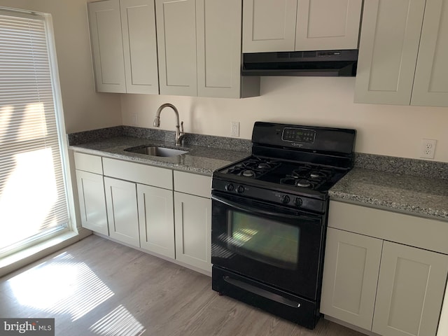 kitchen with stone counters, sink, light hardwood / wood-style flooring, white cabinetry, and black range with gas cooktop