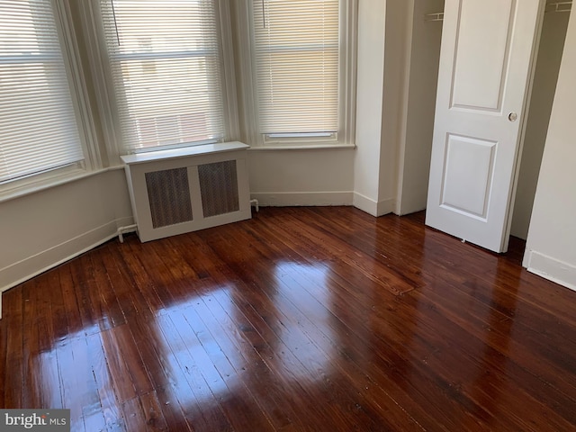 interior space with dark hardwood / wood-style floors, radiator heating unit, and a wealth of natural light