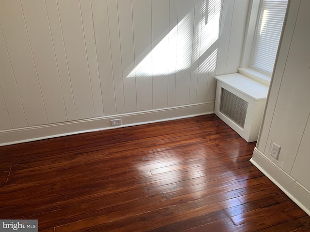 unfurnished room featuring radiator and dark wood-type flooring