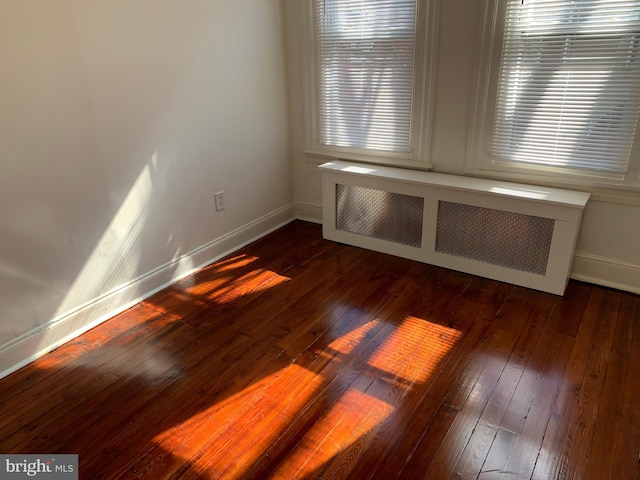 empty room with dark hardwood / wood-style floors and radiator