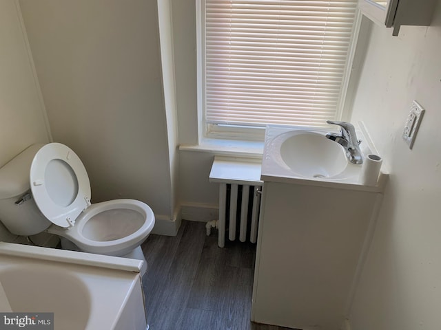 bathroom featuring hardwood / wood-style flooring, vanity, toilet, and radiator heating unit