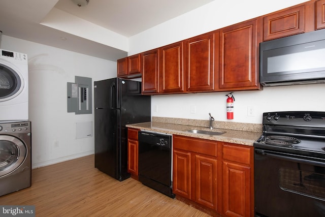 kitchen featuring stacked washer and clothes dryer, light stone counters, sink, black appliances, and light hardwood / wood-style flooring