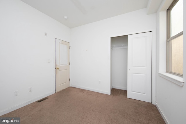 unfurnished bedroom featuring a closet, dark carpet, and multiple windows