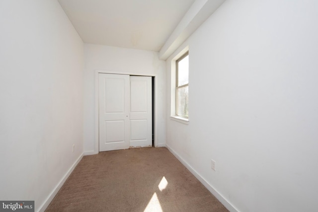 unfurnished bedroom featuring light carpet and a closet