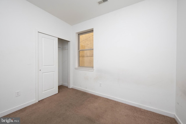 unfurnished bedroom with a closet and dark colored carpet