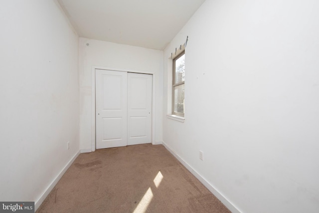 unfurnished bedroom with light carpet and a closet