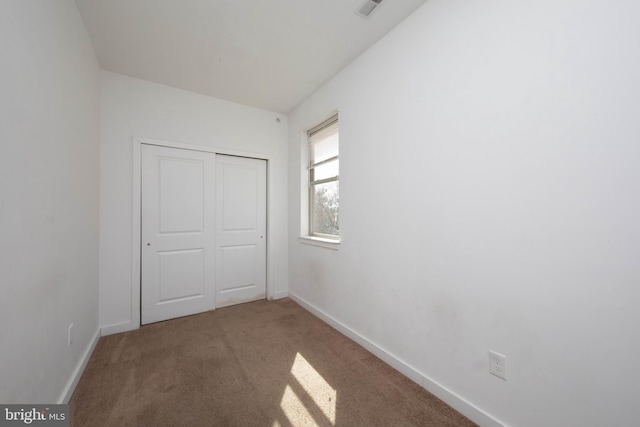 unfurnished bedroom featuring light carpet and a closet