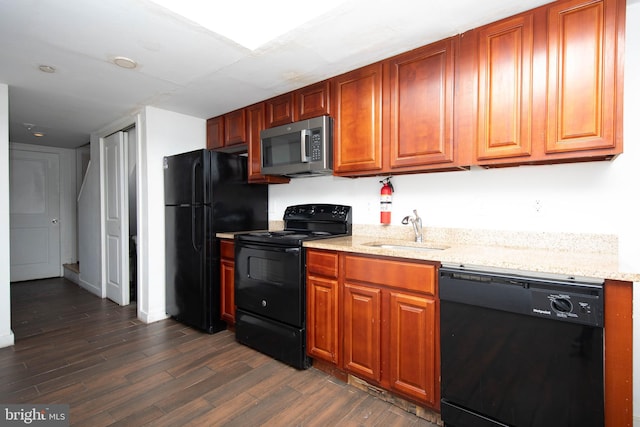 kitchen featuring dark hardwood / wood-style flooring, sink, black appliances, and light stone countertops