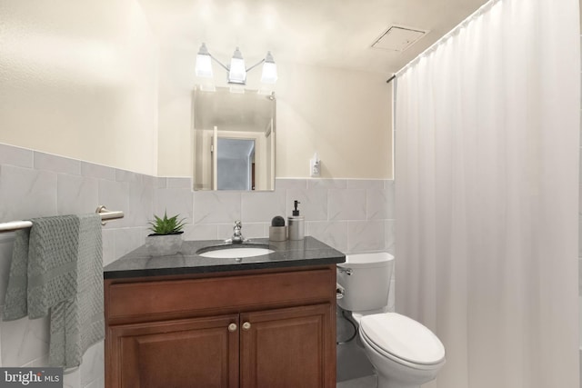 bathroom featuring tile walls, backsplash, vanity, and toilet