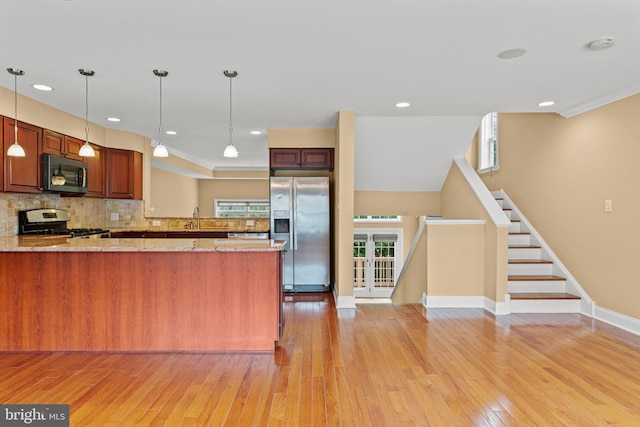 kitchen with light stone counters, tasteful backsplash, light wood-type flooring, stainless steel appliances, and kitchen peninsula