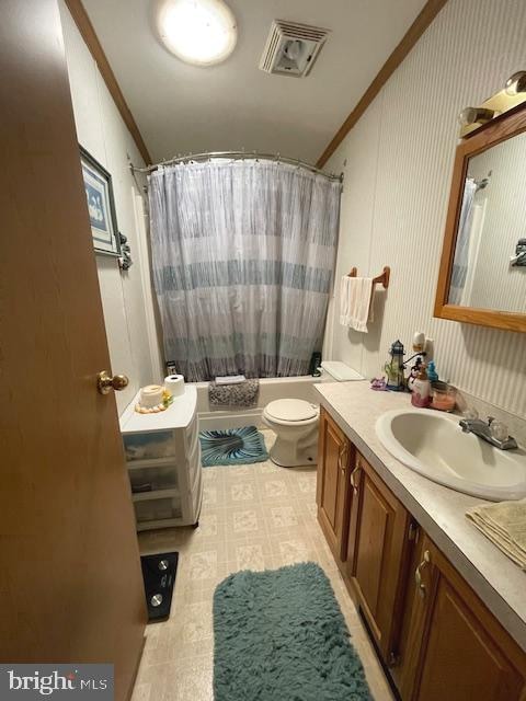 full bathroom with toilet, vanity, shower / bath combo with shower curtain, and ornamental molding