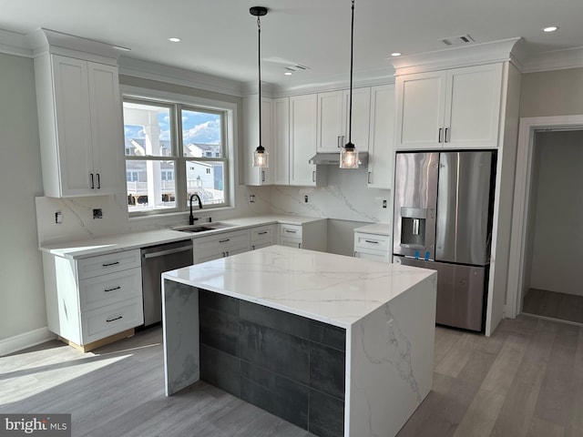 kitchen featuring white cabinets, sink, appliances with stainless steel finishes, decorative light fixtures, and a kitchen island