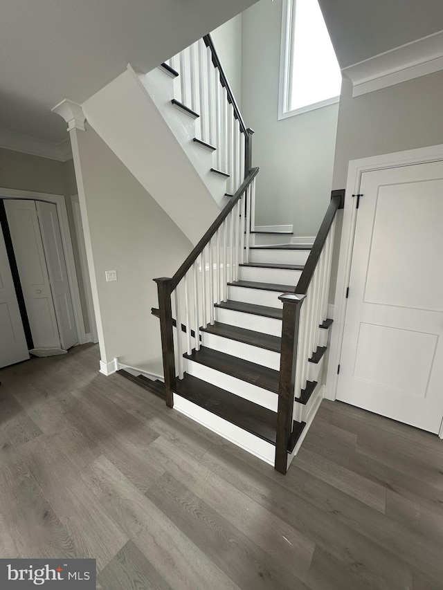 stairs with hardwood / wood-style floors, decorative columns, and crown molding