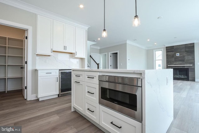 kitchen with wine cooler, white cabinetry, a fireplace, and pendant lighting