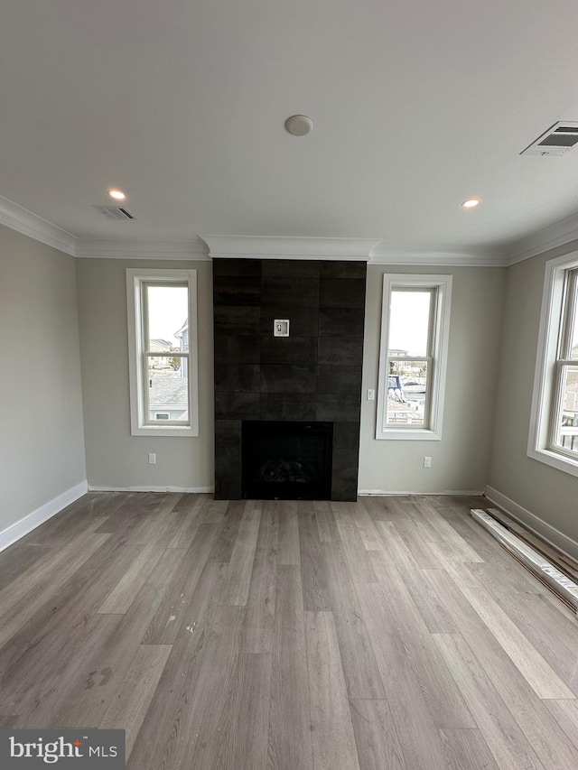 unfurnished living room with a fireplace, light wood-type flooring, and a wealth of natural light