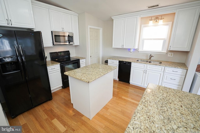 kitchen featuring a kitchen island, sink, light wood-type flooring, white cabinetry, and black appliances